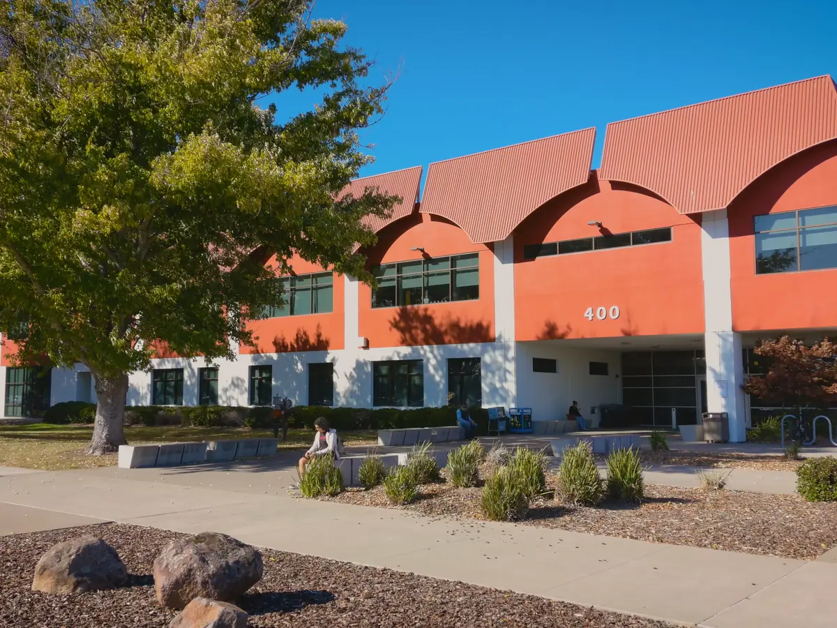 Exterior of a red-orange Solano Community College building with arched roof sections, large windows, landscaped walkways, and the number 400 above the entrance.