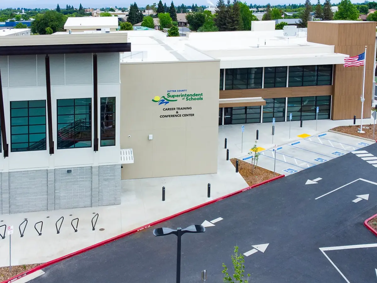 Aerial view of the Sutter County Career Training Center campus building, showing the white and tan facility, school signage, parking lot, crosswalks, and surrounding trees.