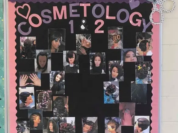 A hallway bulletin board at West Mecklenburg High School displays student cosmetology work, with hairstyle and manicure photos arranged around large pink-and-white 'Cosmetology 1 & 2' lettering.
