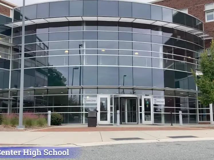 Exterior entrance of Career Center High School, showing a curved glass-fronted entry between brick wings.