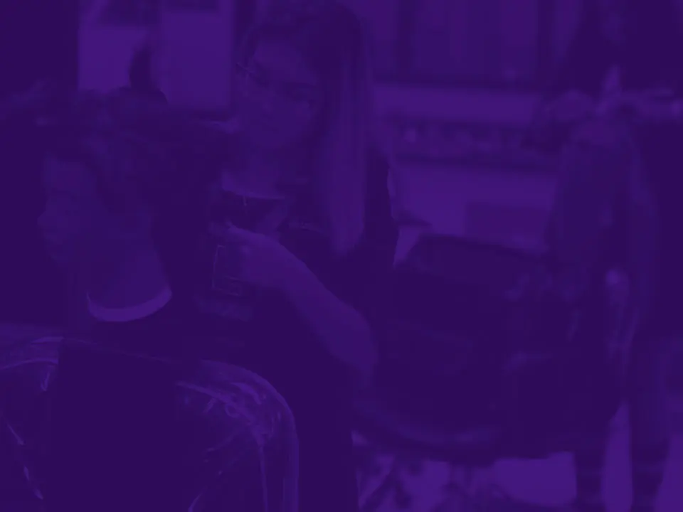 Purple-tinted interior of a cosmetology classroom or student salon with styling stations and salon equipment.