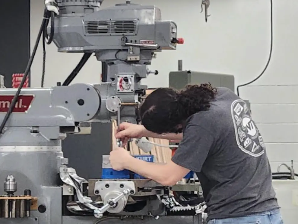 A student operates a large milling machine in a Whittier Tech technical training room.