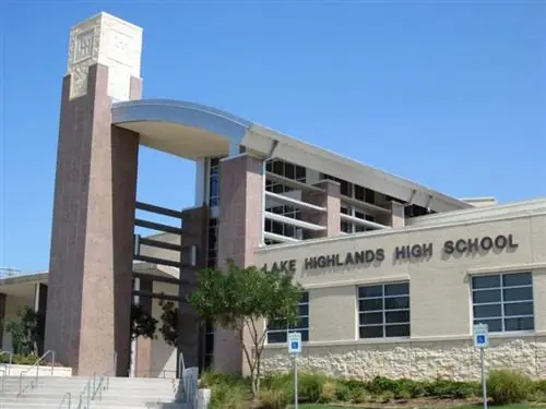 Exterior view of Lake Highlands High School, showing the school name on the front facade, a tall brick tower, covered entrance, windows, stairs, and a clear blue sky.