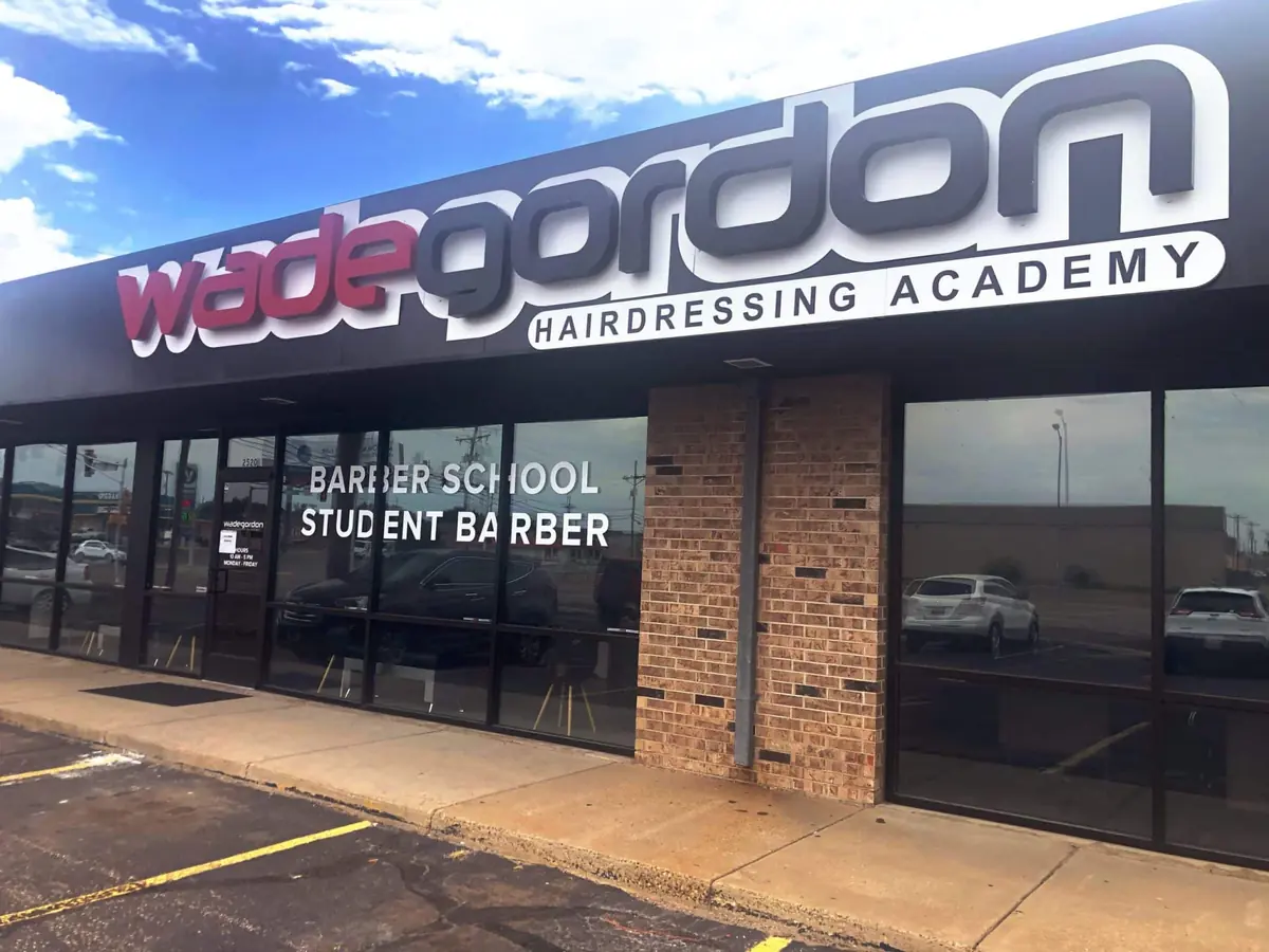 Exterior storefront of Wade Gordon Hairdressing Academy, with a large Wade Gordon sign above glass windows labeled “BARBER SCHOOL” and “STUDENT BARBER.”