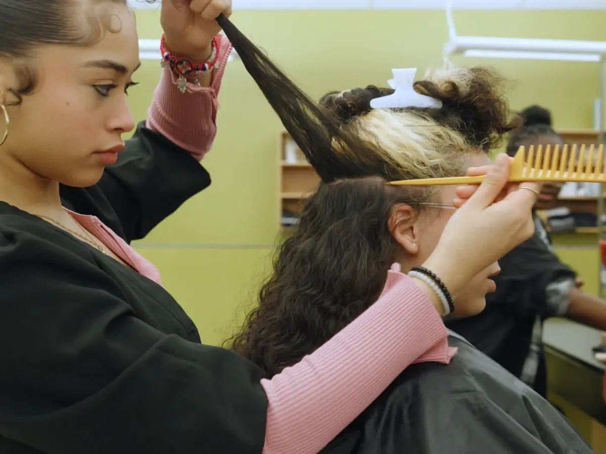 A student styles a client's hair in the Providence Career & Technical Academy cosmetology classroom salon.