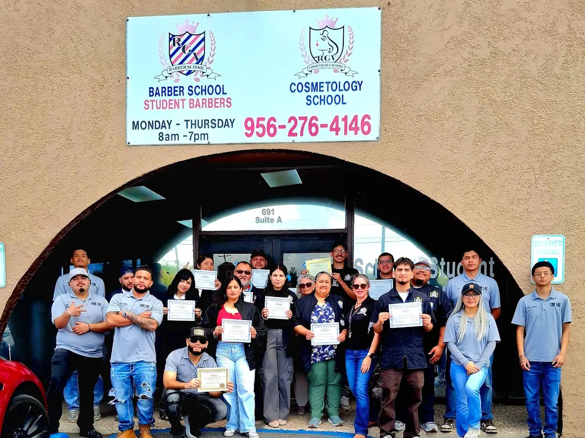 A group of students and staff holding certificates stands outside the RGV Barber & Cosmetology School entrance. The facade sign identifies the Barber School and Cosmetology School and displays phone number 956-276-4146; the entrance marker reads 691 Suite A.