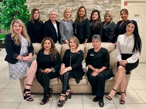 Group portrait of eleven Salon & Spa Institute staff members, dressed mostly in black, posed around a beige sofa in a bright tiled interior with a stone-textured wall and a large green plant.