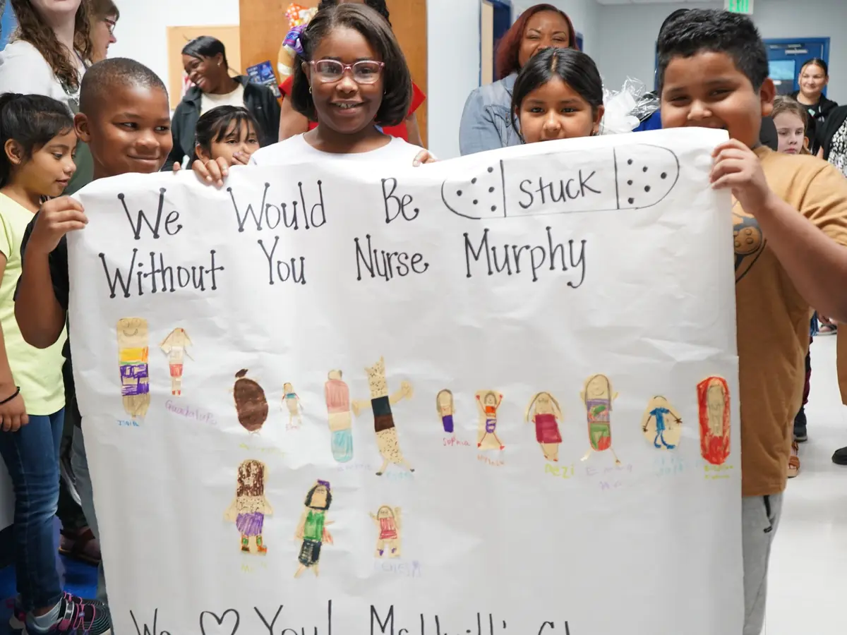 Chilton ISD students and adults hold a handwritten thank-you banner for Nurse Murphy in a school hallway.