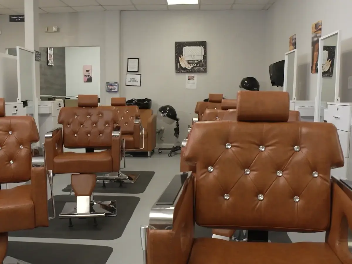 Interior of a barber academy classroom with rows of brown barber chairs, mirrors, and styling stations.