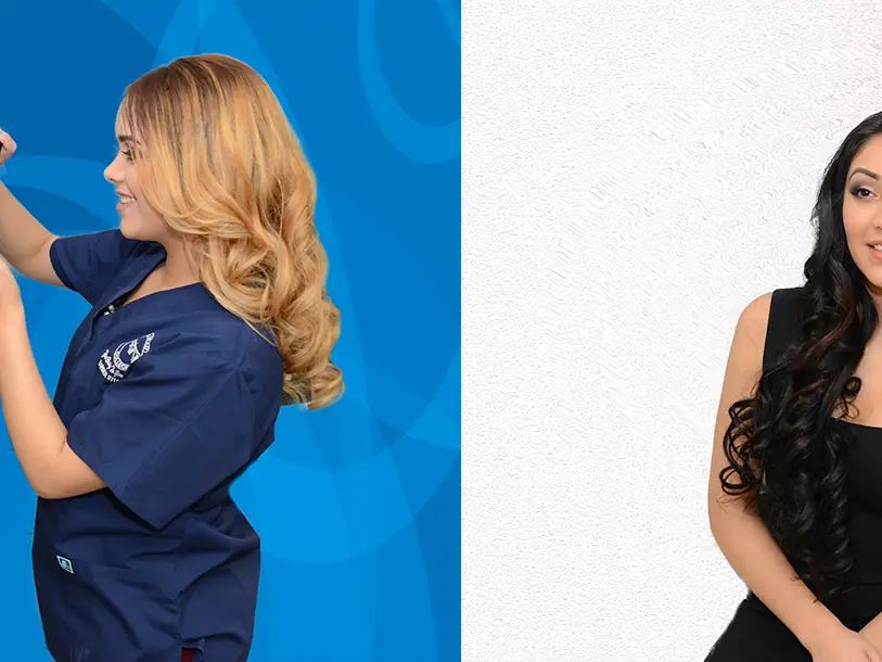 A cosmetology student with long dark hair sits while a blonde stylist in blue scrubs works on her hair against a blue-and-white backdrop.