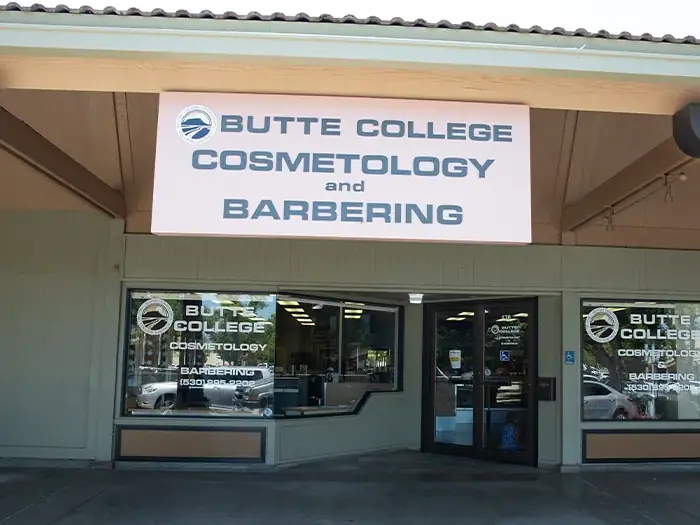 Exterior entrance of the Butte College Cosmetology and Barbering Center, with a large Butte College sign above the glass doors.