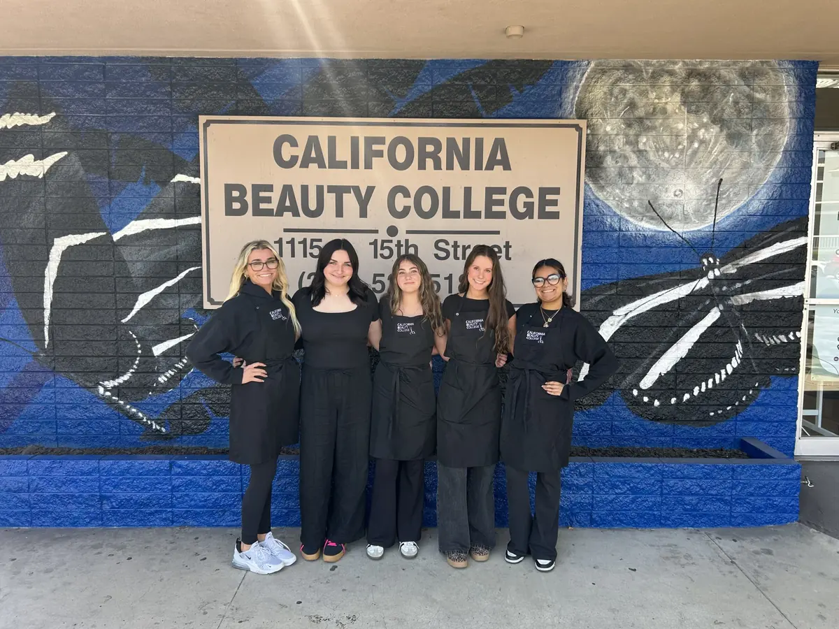 Five people stand outside California Beauty College in front of a blue mural and a sign displaying the college name and 1115 15th Street address.