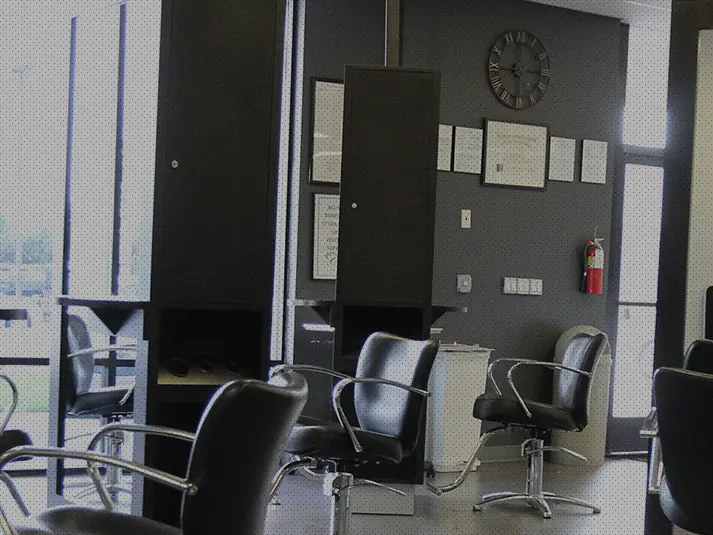 Interior of a cosmetology salon with styling chairs, mirrors, workstations, and large windows.