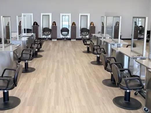 Bright salon floor at Fremont Beauty College's Richmond campus with rows of styling chairs, mirrors, and workstations.