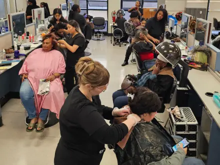 Laney College cosmetology students provide hair services to clients at styling stations in a bright student salon classroom.