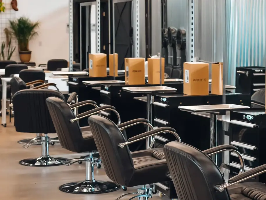 Cosmetology salon classroom with rows of styling chairs, mirrored stations, and boxed products on the counters.