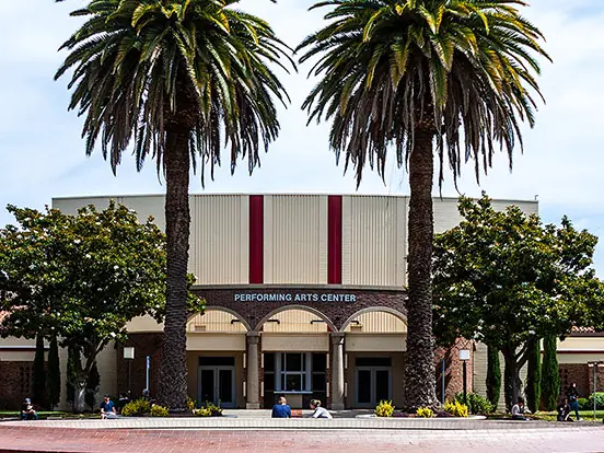 Sacramento City College’s Performing Arts Center, a low brick-and-stucco building framed by two tall palm trees and landscaping.