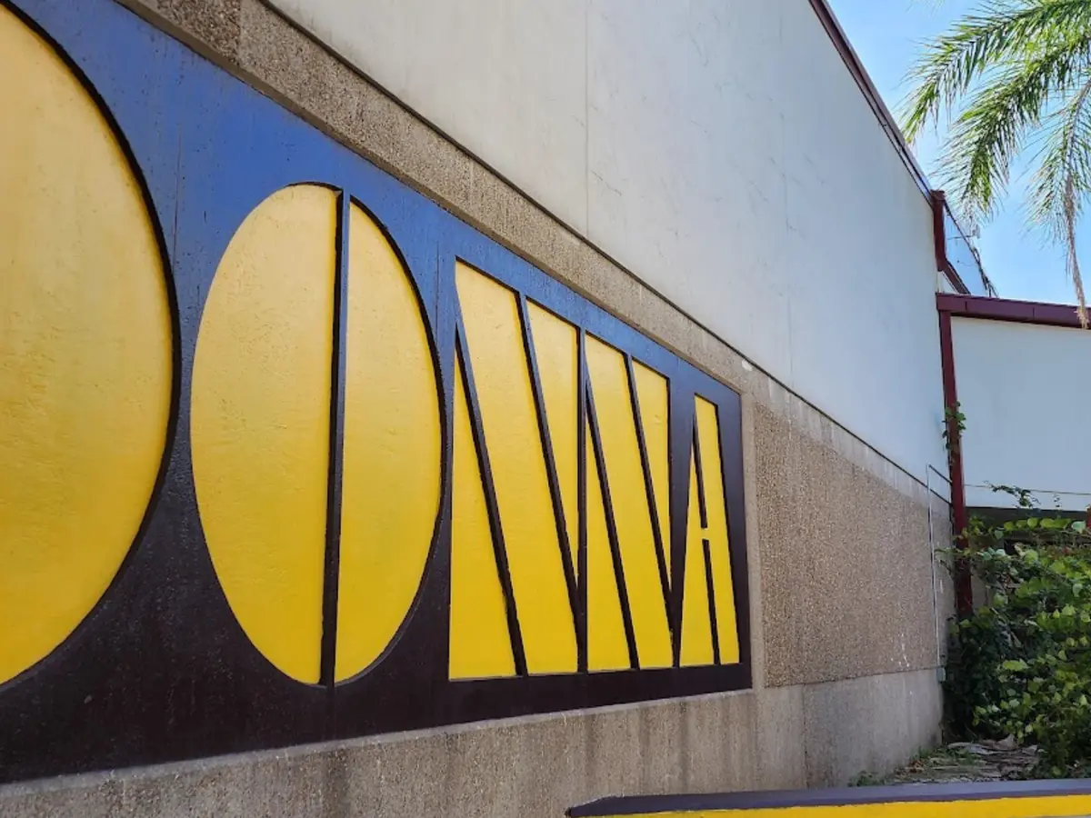 Donna High School exterior with large yellow DONNA lettering on a dark wall, palm trees, and the covered campus entrance walkway.